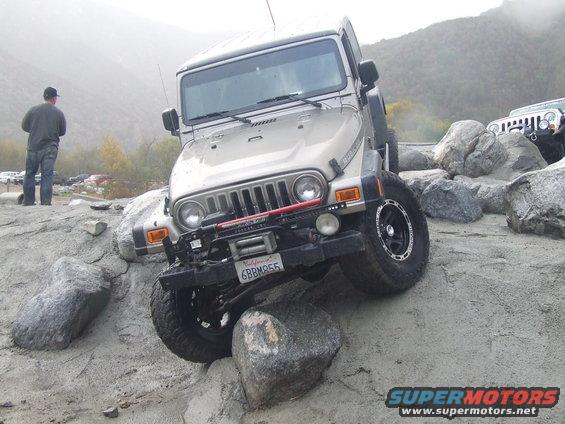 Jeep Wrangler TJ navigating rocky terrain, another Jeep visible in background