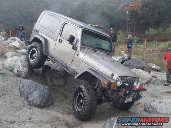 Jeep Wrangler Rubicon climbing over rocks with people watching