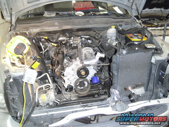 Engine bay with parts removed for repair. Tools and a yellow work light are visible