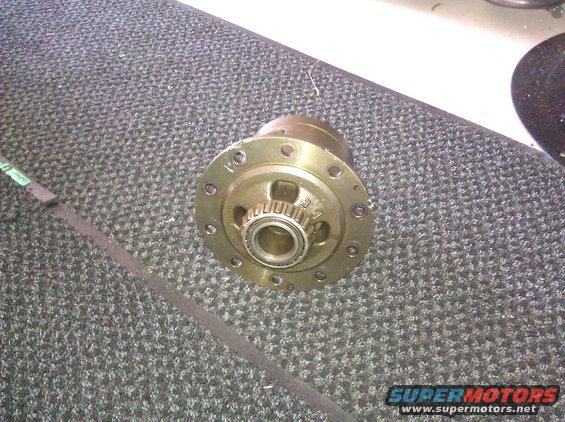 Differential carrier with bearing and gear teeth, on a grey carpeted surface