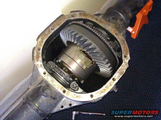 Differential housing with exposed ring and pinion gears, showing wear and a socket wrench nearby