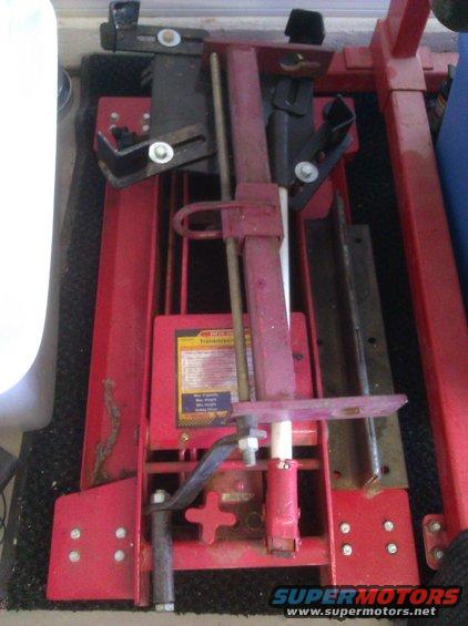 Red hydraulic jack with a yellow and blue label showing specifications