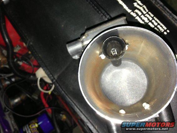 Close-up of an engine intake part with visible metal discoloration and mounting hardware