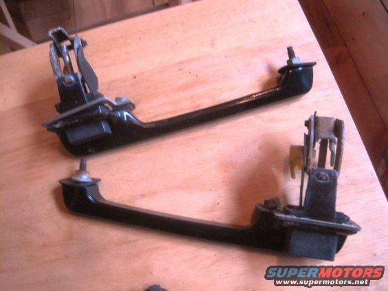 Two black door handles with metal mechanisms on a wooden surface