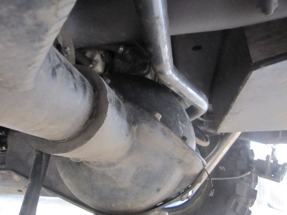 Close-up of a vehicle's rear differential and suspension parts, including a driveshaft and tire