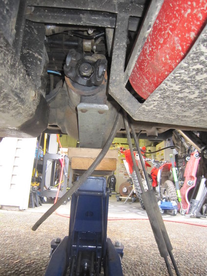 Driveshaft U-joint and differential housing supported by a blue jack and wooden blocks