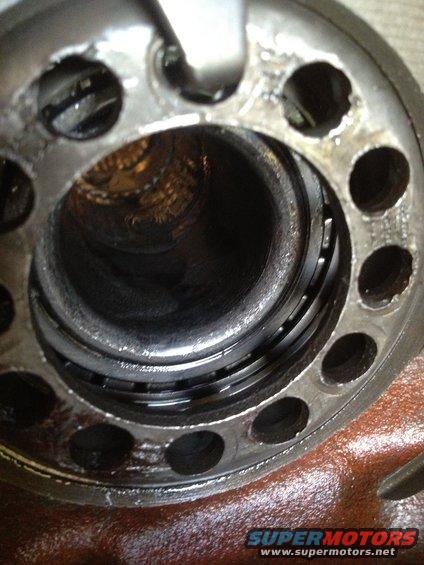 Close-up of a damaged bearing race within a metal housing with bolt holes