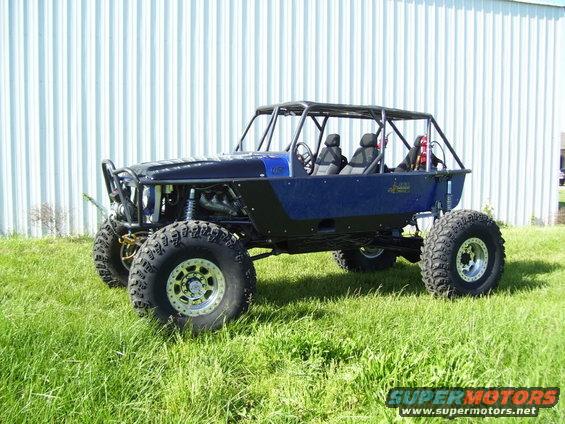 Custom blue and black off-road buggy with large tires and roll cage parked on grass