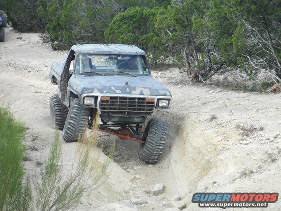 Modified 1979 Ford Bronco climbing a dirt trail with large tires