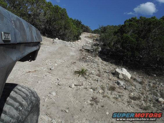 Side view of camouflage SUV on rocky trail. Badge visible