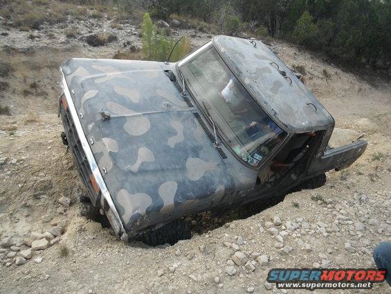 Camouflaged 1979 Ford Bronco stuck in dirt, 3q-front view