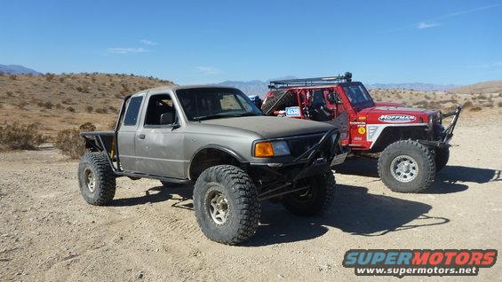 Gray Ford Ranger with big tires parked next to a red Jeep in a desert landscape