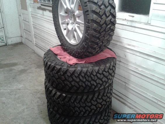 Stack of four off-road tires, one with a silver rim