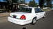 2001 Ford Crown Victoria - A white 2001 Ford Crown Victoria is parked on a residential street, viewed from the rear quarter angle.