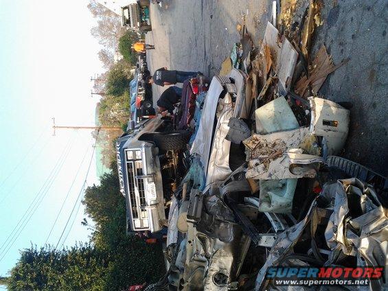 Pickup truck with 'BESTMADRE' on the side, surrounded by debris