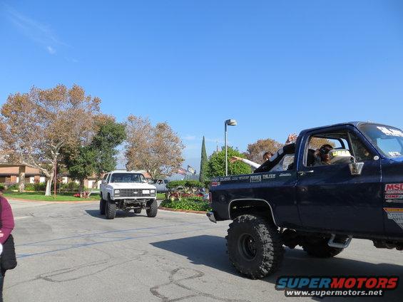 White SUV with large tires driving on a road