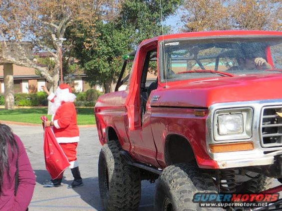 Red 1978 Ford Bronco with lifted suspension, Santa Claus nearby