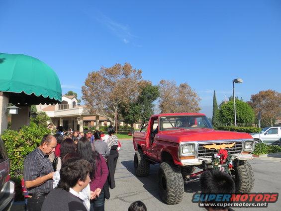Lifted red pickup truck with a Batman logo on the grille and holiday decorations
