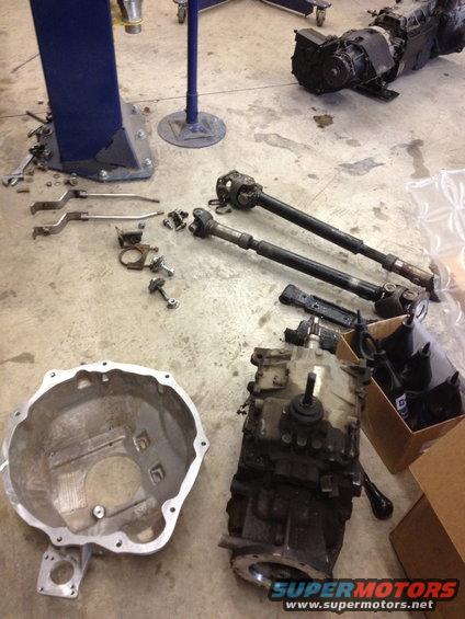 Transmission, bell housing, and driveshafts laid out on concrete floor