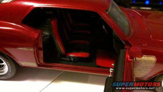 Red 1970 Ford Mustang model with black and red interior, driver's side door open, viewed from the side