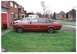 1977 Ford Granada - A red 1977 Ford Granada is parked on a lawn next to a driveway and a house.