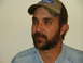 1990 Ford Bronco - A man with a beard wears a Ford baseball cap and a denim shirt.