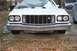 1976 Ford Ranchero - A white 1976 Ford Ranchero is parked outside, its front end covered by a car cover, revealing the grille and bumper.