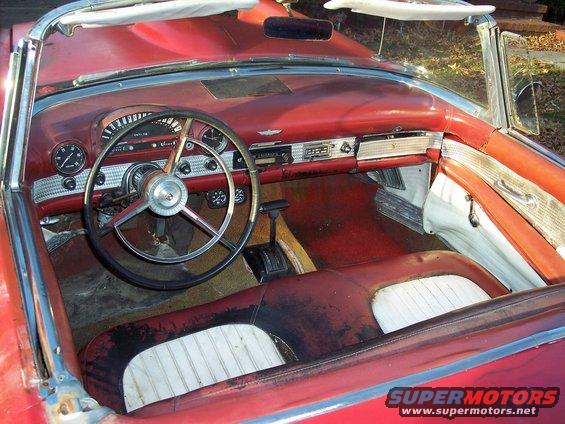 Interior of a red 1956 Ford Thunderbird convertible, showing dashboard, steering wheel, and seats