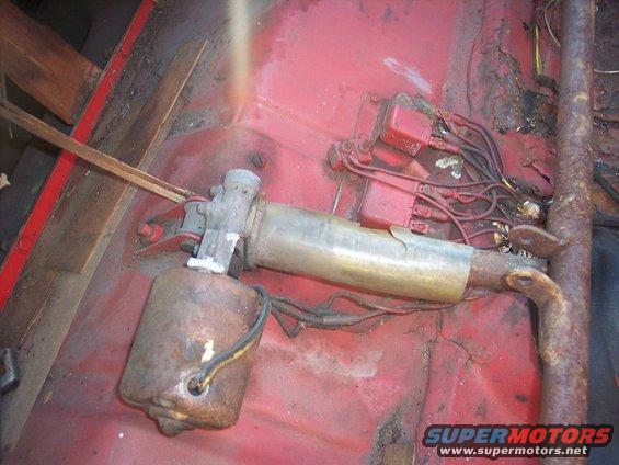 Rusty power window motor and regulator assembly on red floor pan