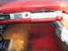 1956 Ford Thunderbird - The interior of a classic car shows a red dashboard with a radio and a textured glove compartment panel.