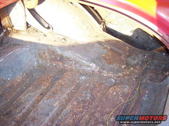 Rusty trunk floor with exposed wires and some corrugated tubing