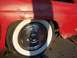 1956 Ford Thunderbird - Close-up of a rusty red 1956 Ford Thunderbird's side, showing a whitewall tire and chrome hubcap.