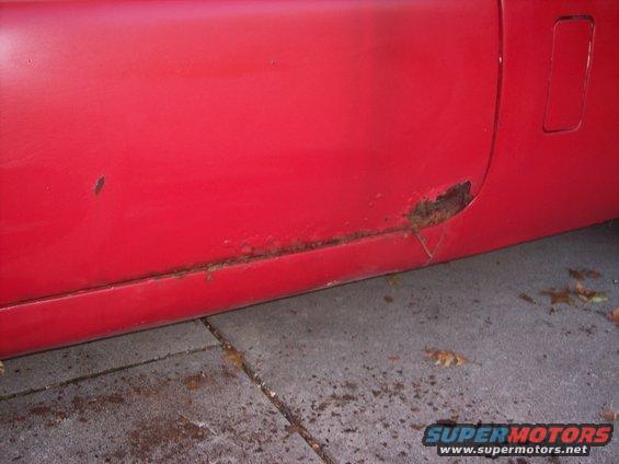 red car door bottom with significant rust damage along the lower edge