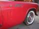 1956 Ford Thunderbird - Close-up of a red car's side fender and wheel, revealing a flat tire and vintage styling details.