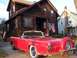 1956 Ford Thunderbird - A red 1956 Ford Thunderbird convertible is parked in front of a house with an American flag.