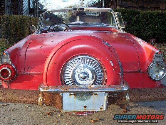 Red 1956 Ford Thunderbird convertible rear view with external spare tire and chrome bumper