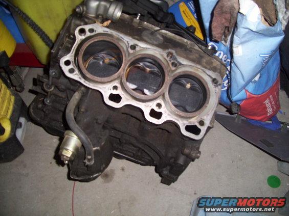 Engine block with three cylinders and pistons visible
