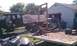 1994 Ford F-250 - A disassembled truck chassis sits in a yard with an engine hoist and various parts on a trailer.
