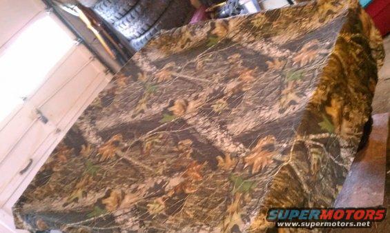 camouflaged object in garage with tires stacked in background