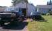 1994 Ford F-250 - Two Ford F-Series trucks, one a chassis and the other a cab, are in a yard with a garage in the background.