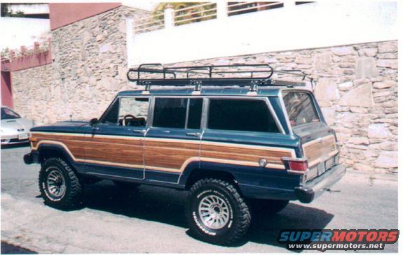 Jeep Grand Wagoneer with wood paneling and roof rack parked on a street