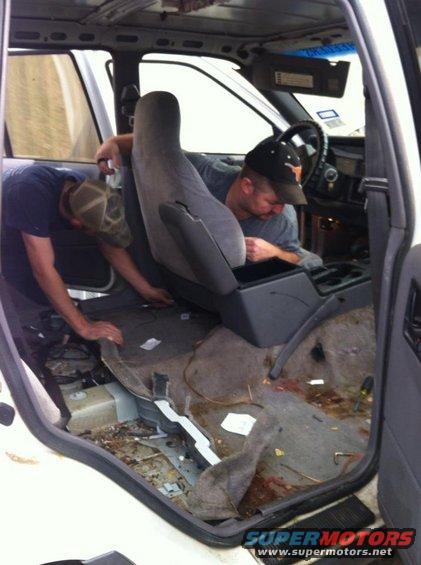 Interior of a vehicle being worked on, showing seats and floor