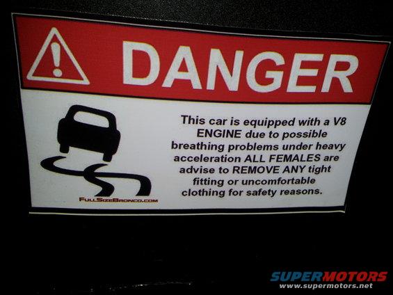 Danger sticker with car graphic and text about V8 engine and clothing