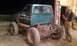 1987 Ford Bronco - A modified Ford Bronco sits in a garage, its frame and suspension clearly visible.