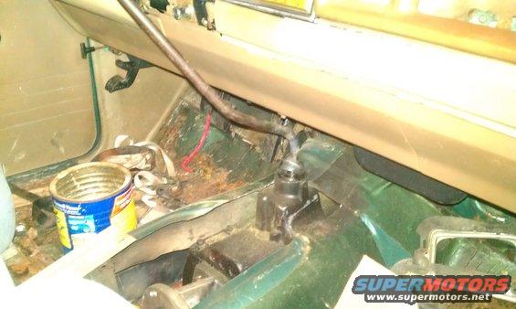 Vehicle interior floor with rust, a shift lever, and an open can