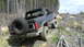 1986 Ford Bronco - This 1986 Ford Bronco is navigating a challenging off-road terrain with dense trees in the background.