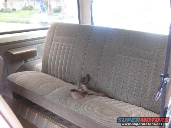 Interior rear bench seat with brown fabric upholstery and seatbelt