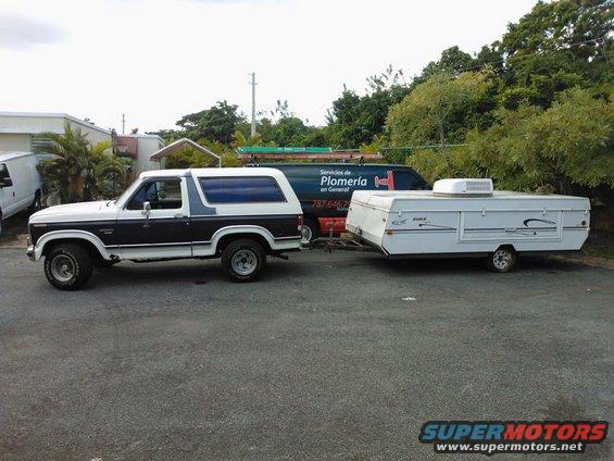 Two-tone white and dark brown Ford Bronco towing a white pop-up camper