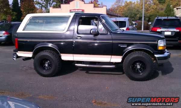 1993 Ford Bronco parked outside, side view. Another SUV is parked behind it
