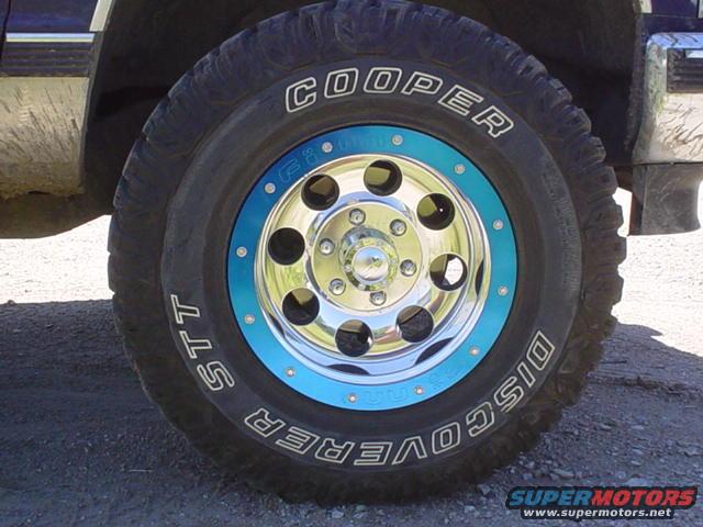Close-up of a Cooper Discoverer STT tire on a chrome rim with a blue accent ring